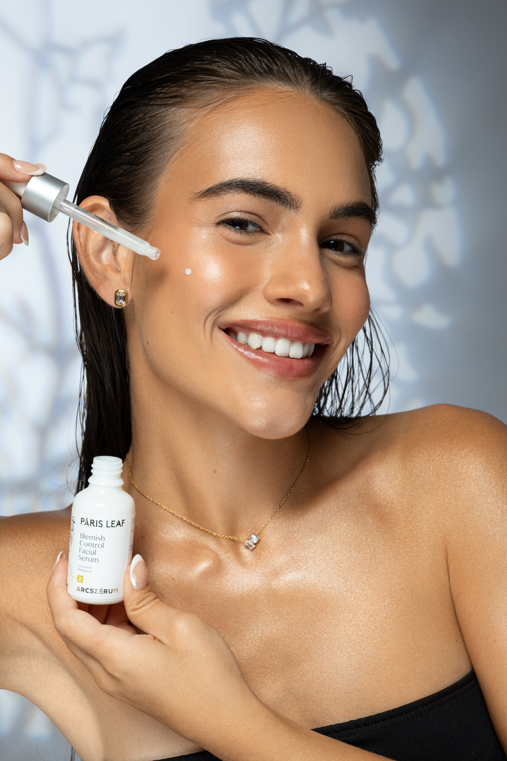 Woman applying Parisleaf Blemish Control Facial Serum to her cheek with a dropper.
